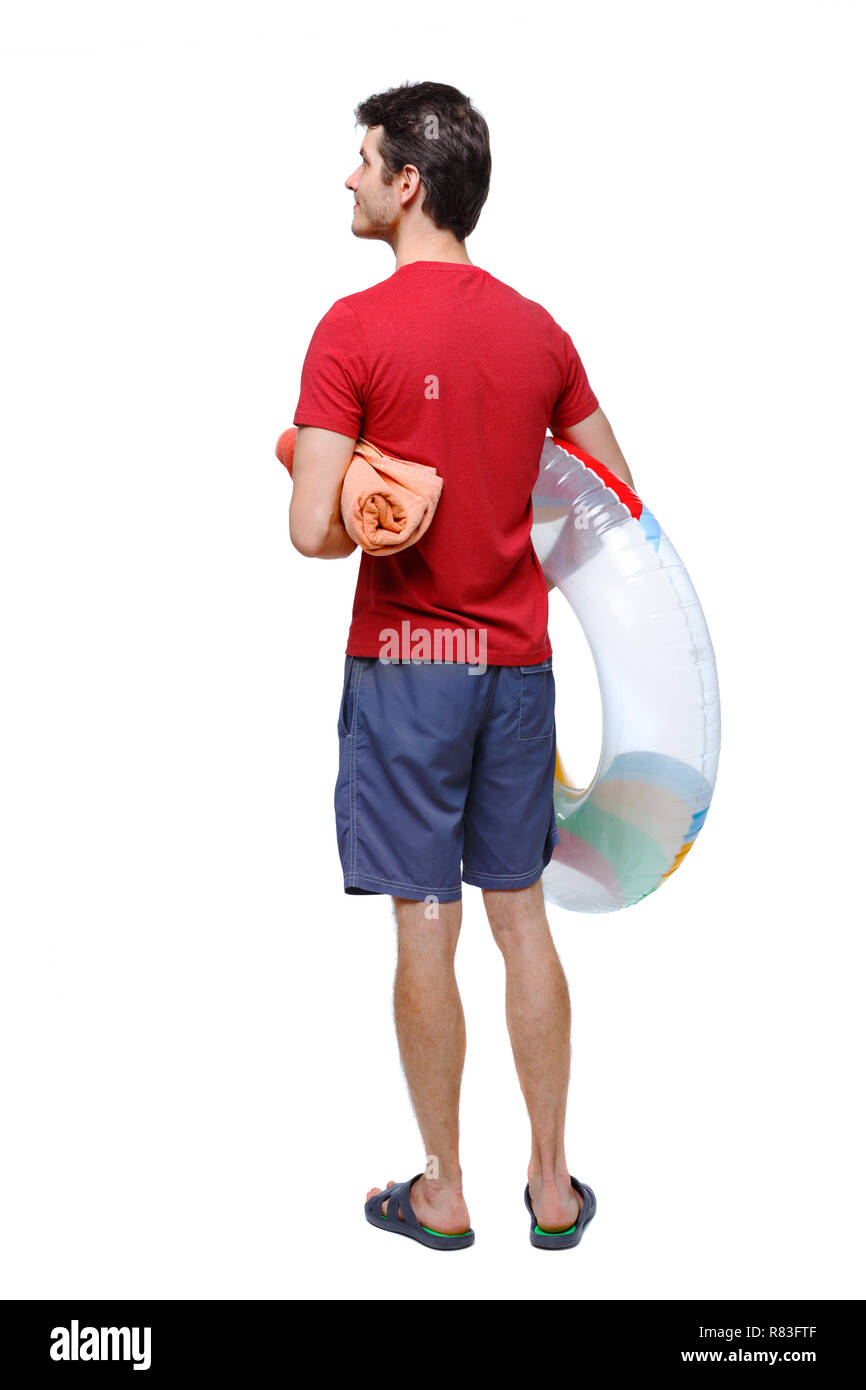 Vista posteriore di un uomo in pantaloncini corti con un cerchio gonfiabile. Il ragazzo sulla spiaggia. Vista posteriore di raccolta persone. vista posteriore di persona. Isolate su wh Foto Stock