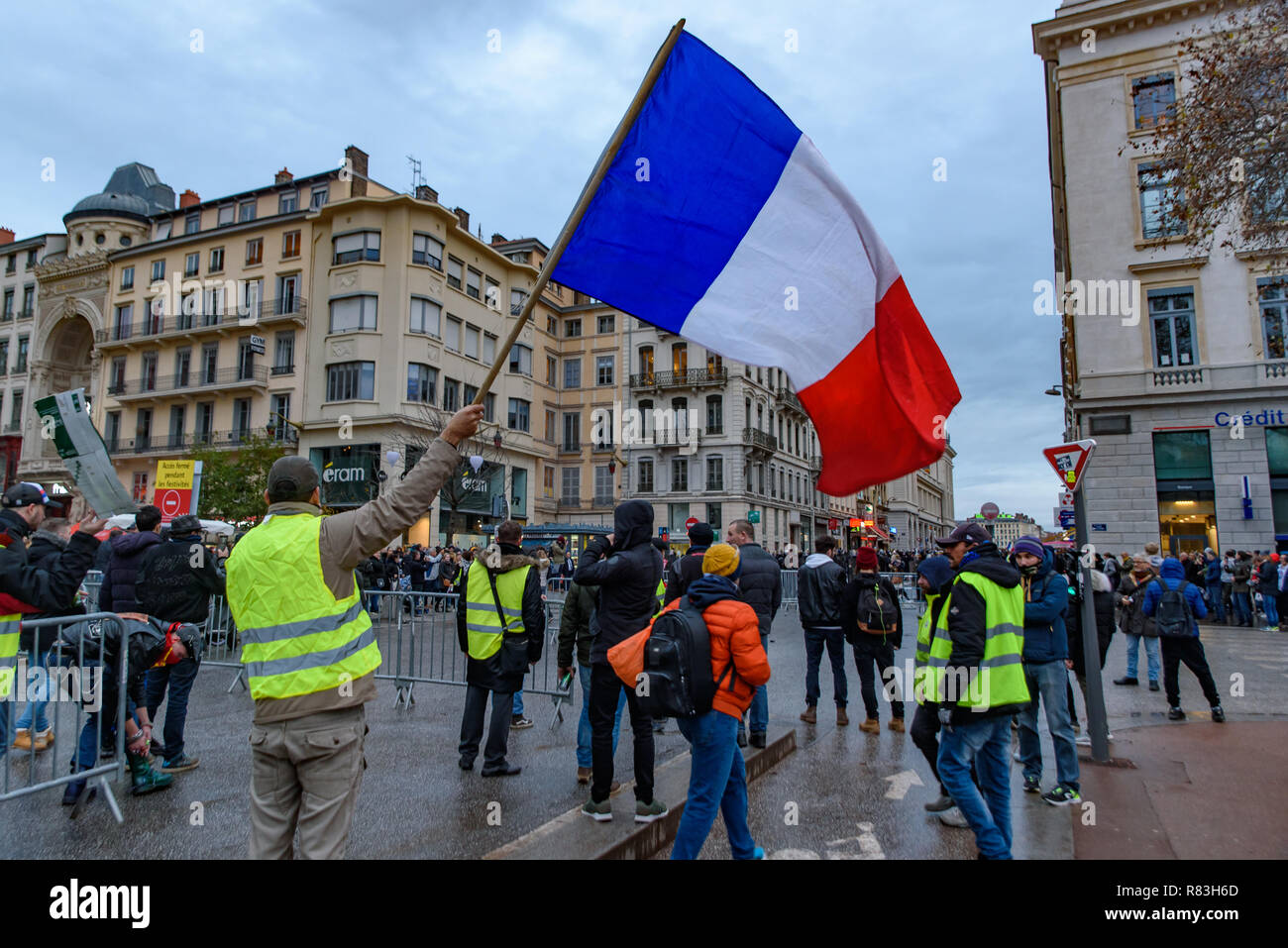 Giubbotti di giallo (Gilets Jaunes), protesta contro le tasse sul carburante, il governo e il presidente francese Macron. Un manifestante è stato sventola bandiera francese a Lyon, Francia Foto Stock
