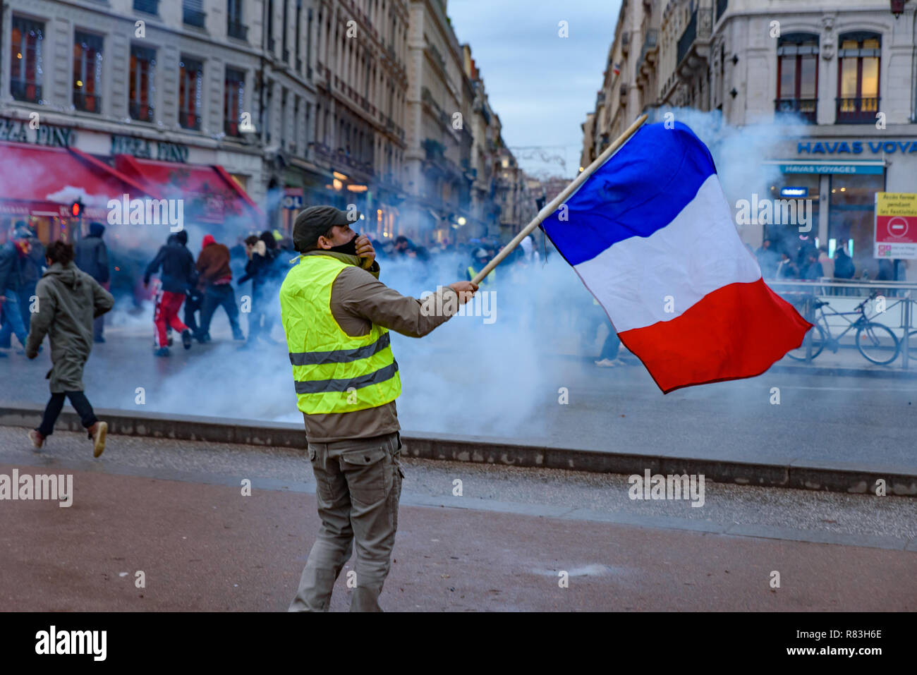 Giubbotti di giallo (Gilets Jaunes), protesta contro le tasse sul carburante, il governo e il presidente francese Macron. Un manifestante è stato sventola bandiera francese a Lyon, Francia Foto Stock