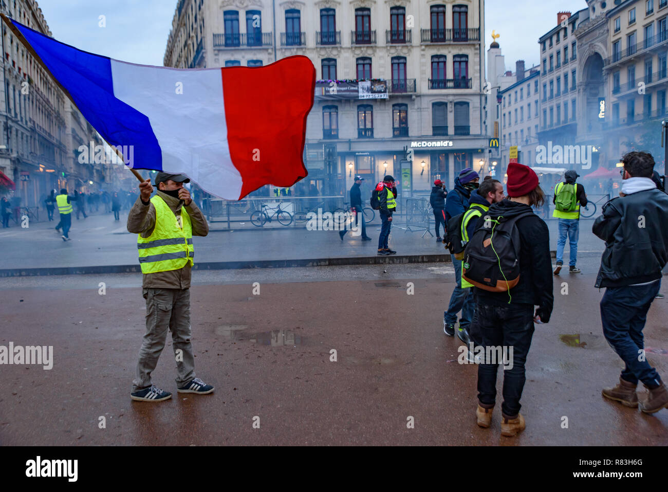 Giubbotti di giallo (Gilets Jaunes), protesta contro le tasse sul carburante, il governo e il presidente francese Macron. Un manifestante è stato sventola bandiera francese a Lyon, Francia Foto Stock