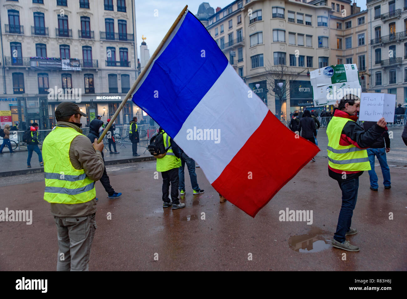 Giubbotti di giallo (Gilets Jaunes), protesta contro le tasse sul carburante, il governo e il presidente francese Macron. Un manifestante è stato sventola bandiera francese a Lyon, Francia Foto Stock