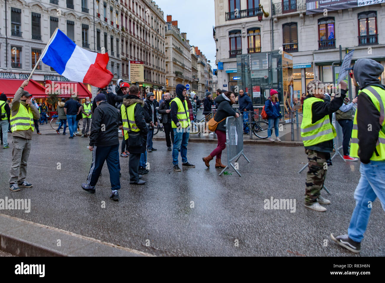 Giubbotti di giallo (Gilets Jaunes), protesta contro le tasse sul carburante, il governo e il presidente francese Macron. Un manifestante è stato sventola bandiera francese a Lyon, Francia Foto Stock