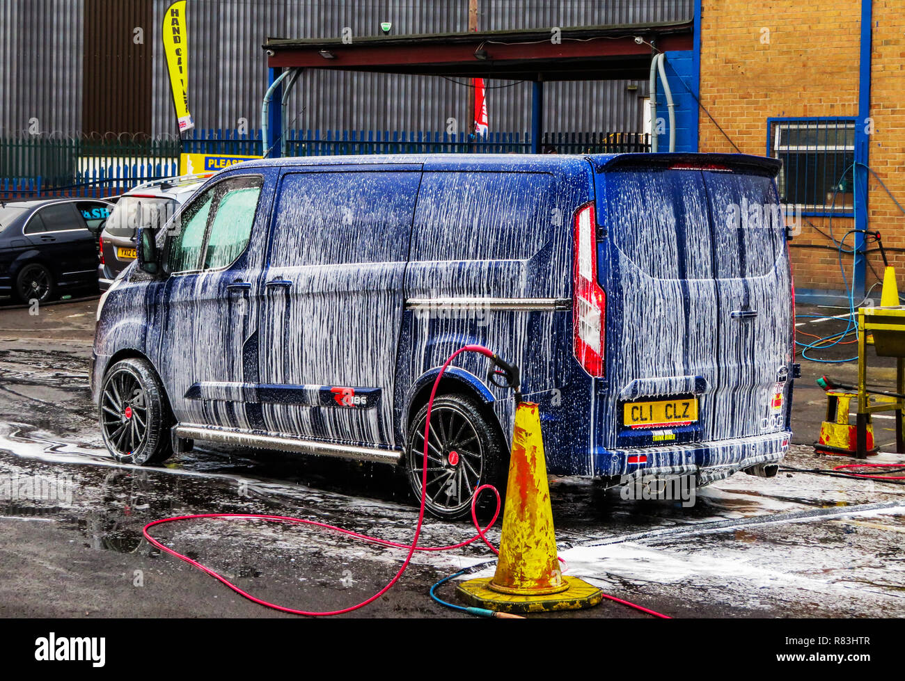 Acqua e getto di schiuma spruzzata su un veicolo pronto per lavare a mano off a Rotherham, South Yorkshire, Inghilterra Foto Stock