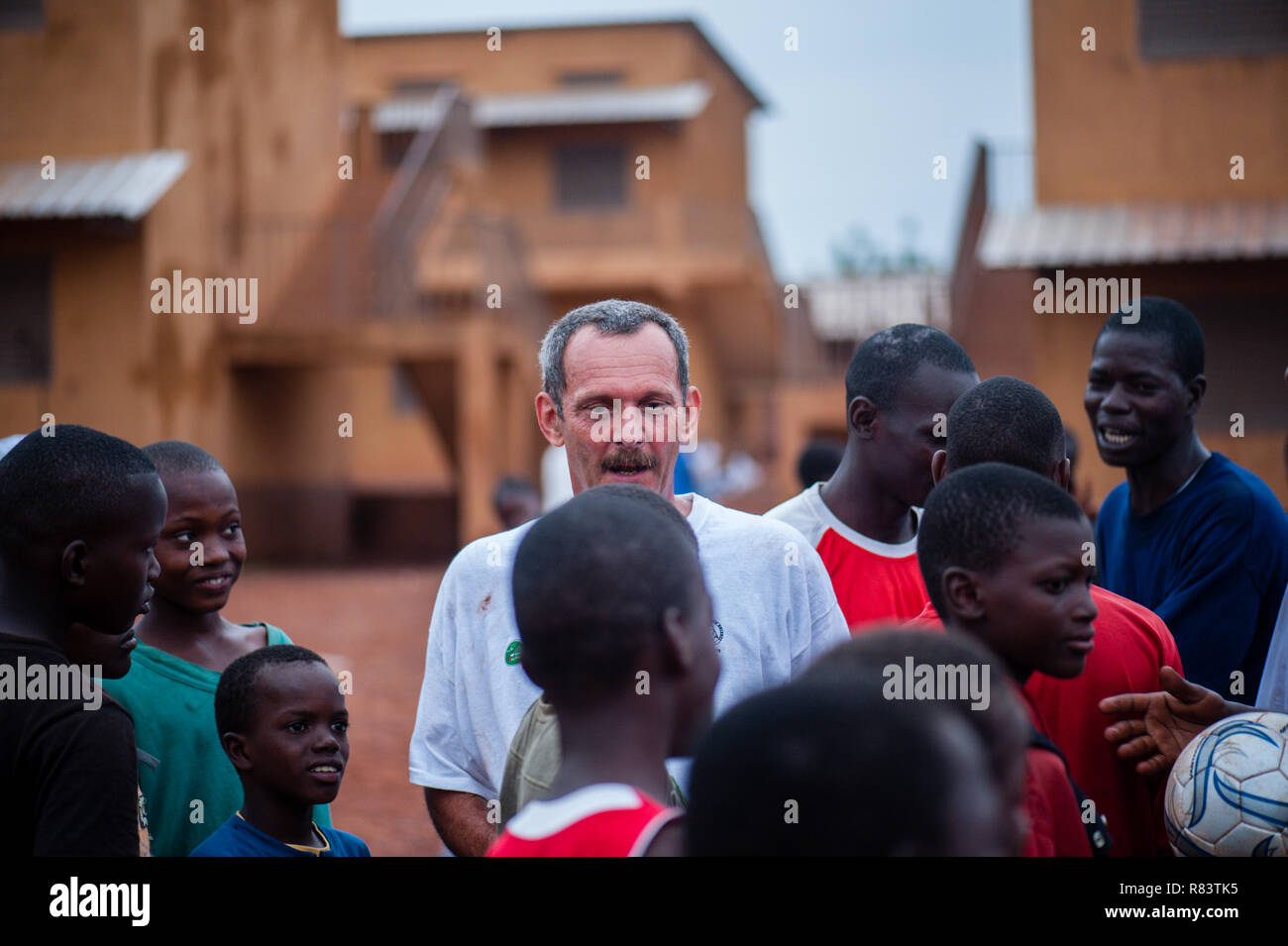 Mali, Africa. Bianco maturo caucasica volontario gode di giocare con i bambini in un villaggio rurale vicino a Bamako. Foto Stock