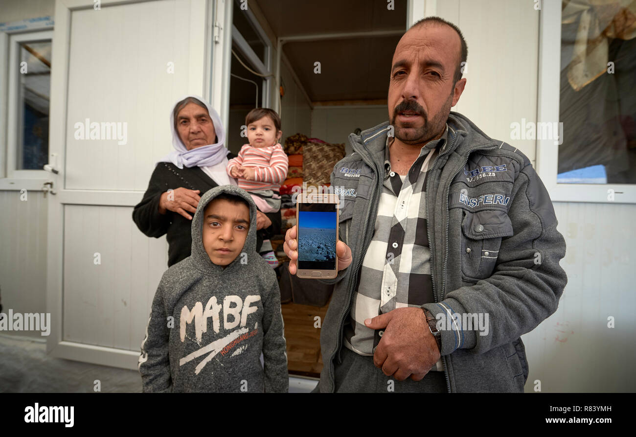 Abbo Bobbi mostra una foto ha catturato sul suo telefono delle rovine della sua casa di famiglia, distrutto dalla guerra nella regione di Sinjar dell'Iraq. Foto Stock