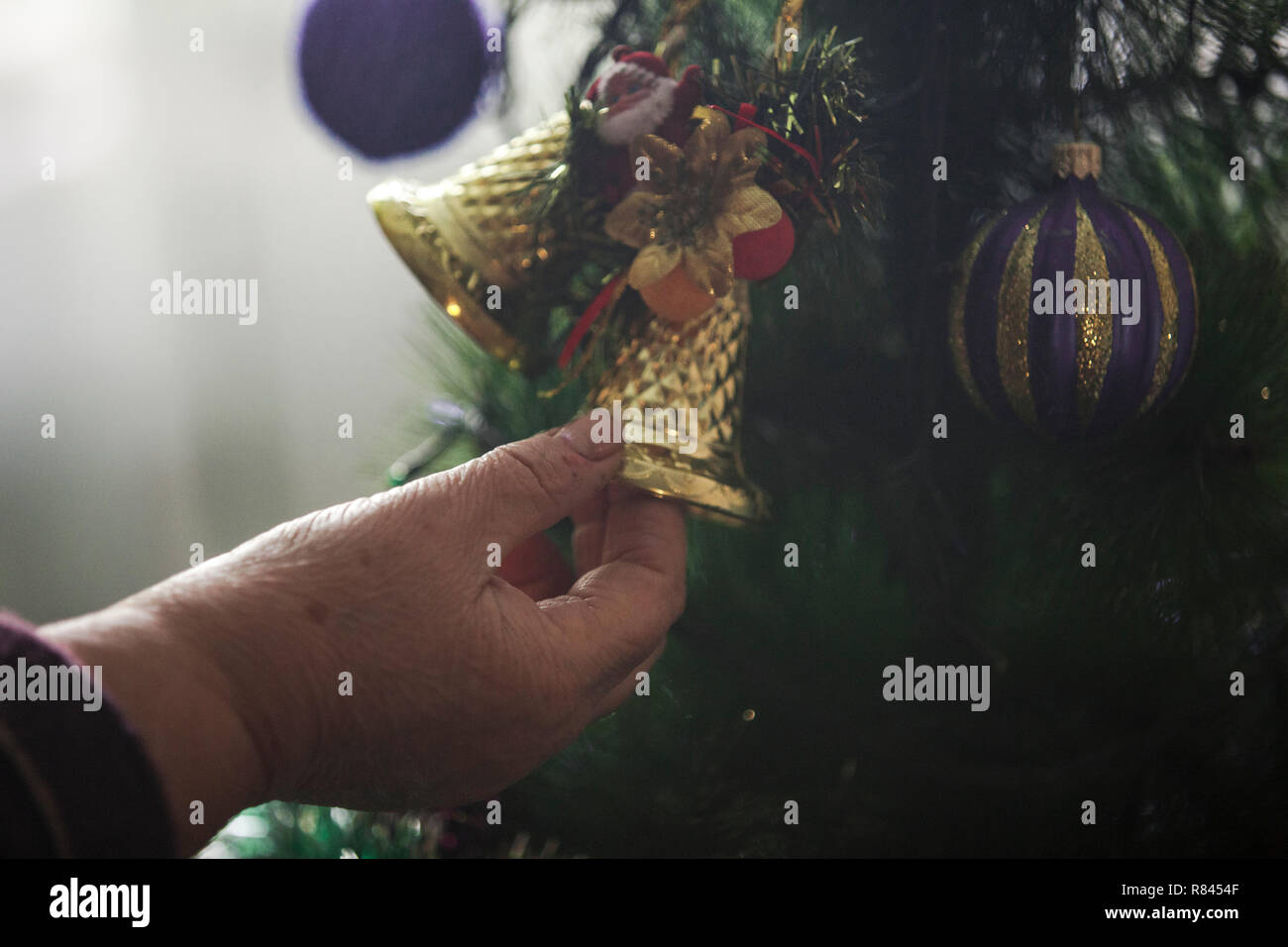 Le mani della donna più anziana decorare albero di Natale Foto Stock