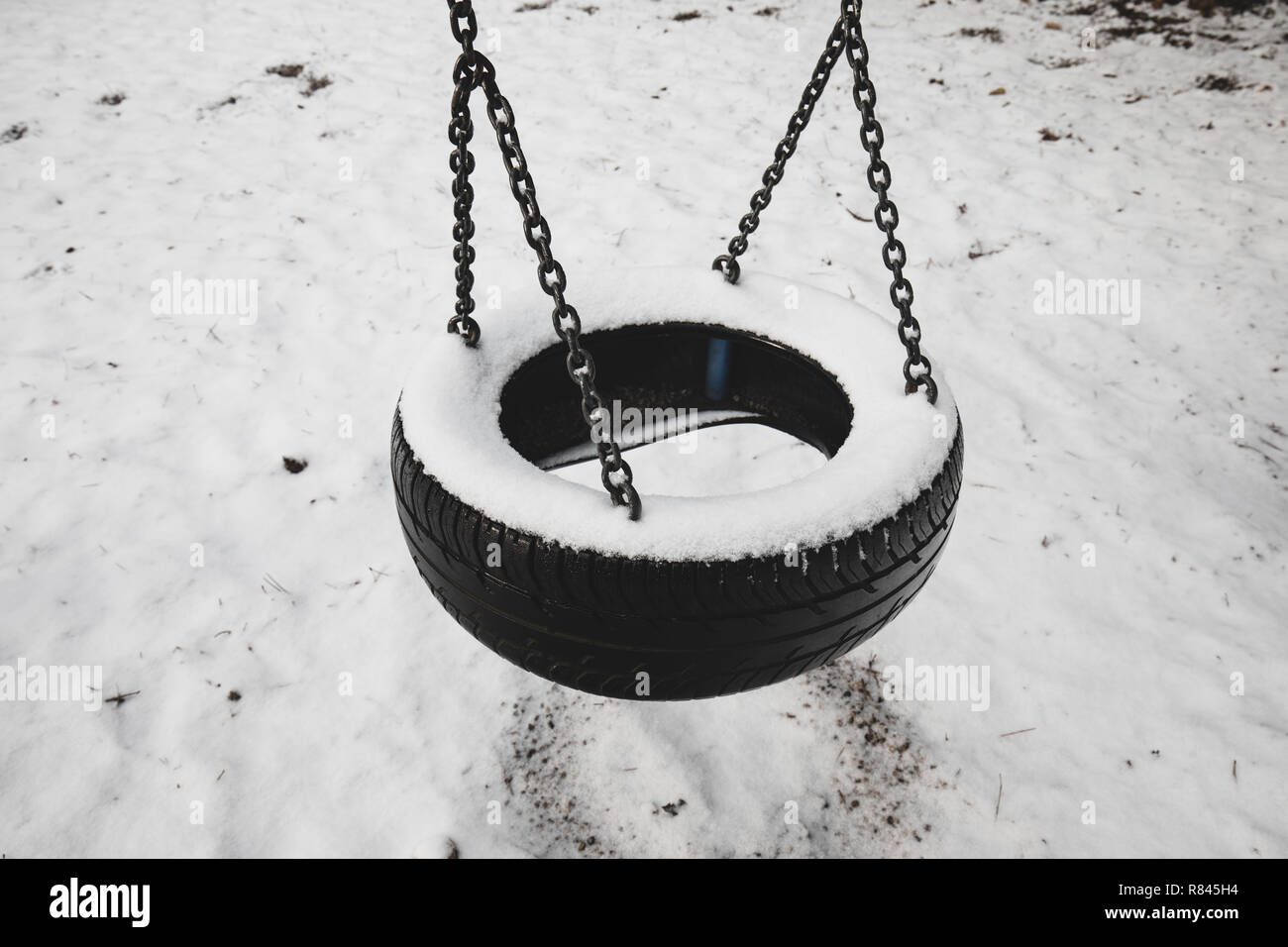 Vecchio abbandonato insieme di pneumatico oscilla coperto di neve contro inverno paesaggio forestale dello sfondo. Ricordi di infanzia concetto in Austria inferiore Foto Stock