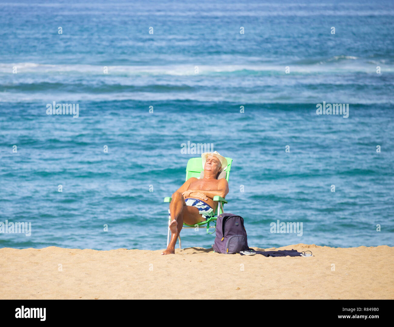 Uomo anziano a prendere il sole sulla spiaggia in Spagna. Foto Stock