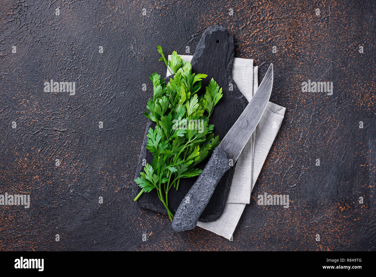 Sfondo culinario con coltello, il prezzemolo e il bordo di taglio Foto Stock