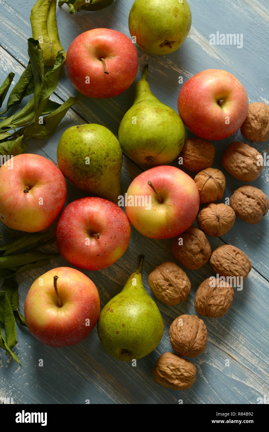 Pila di mele, pere e noci su blu tavolo in legno - primo piano Foto Stock