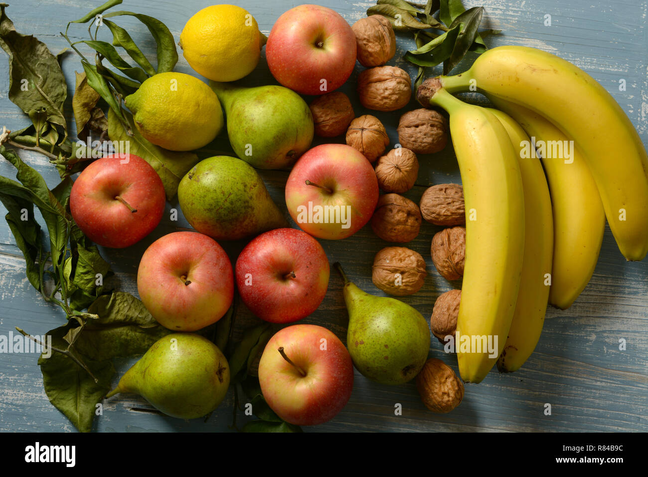 Pila di mele, pere, noci e banane sul blu chiaro Tavolo in legno - primo piano Foto Stock