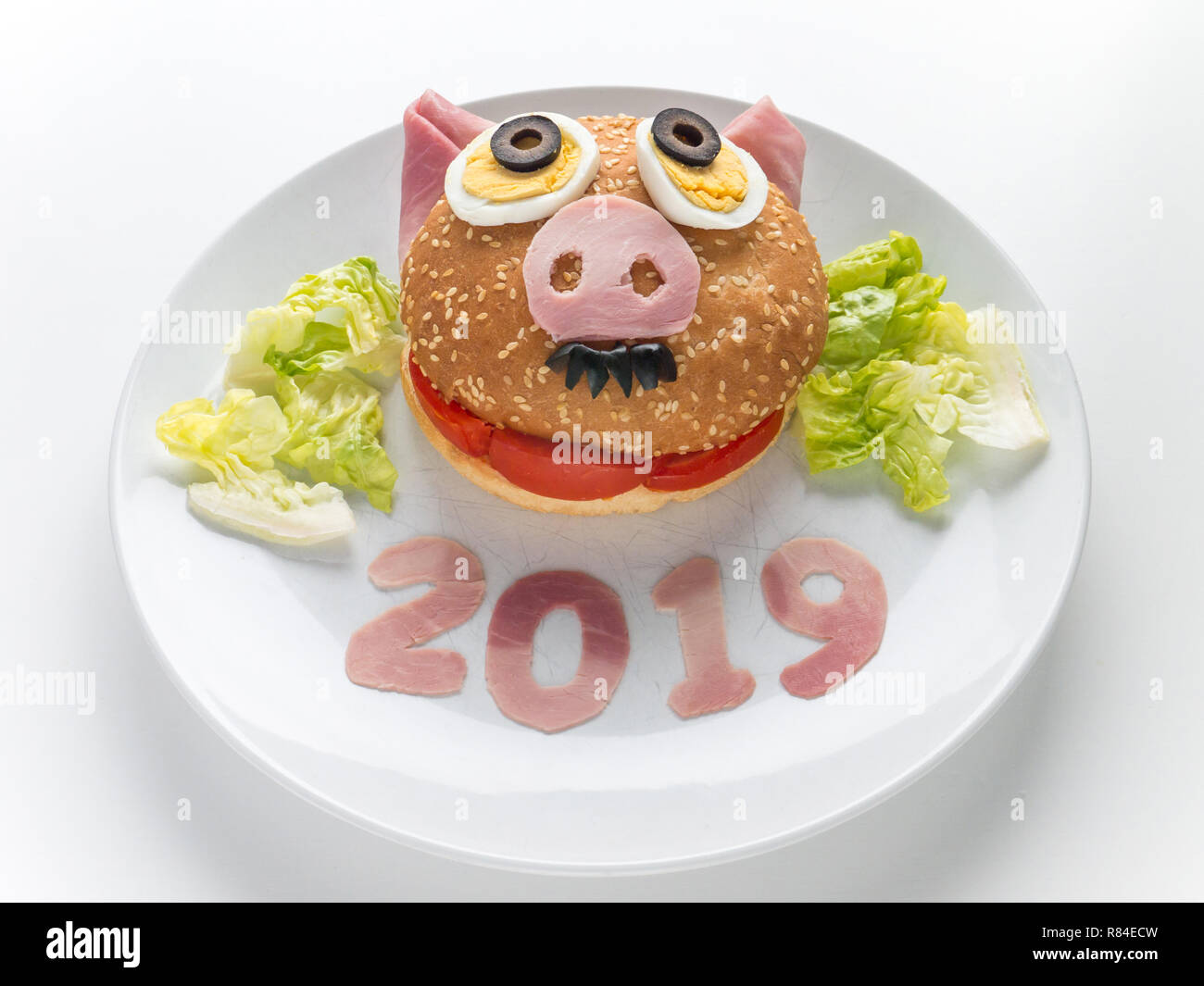 Kids burger, insalata di lattuga e 2019 cifre del prosciutto di maiale come un simbolo del nuovo anno. Animali oroscopo cinese. Divertente maialino maschio sandwich. Foto Stock