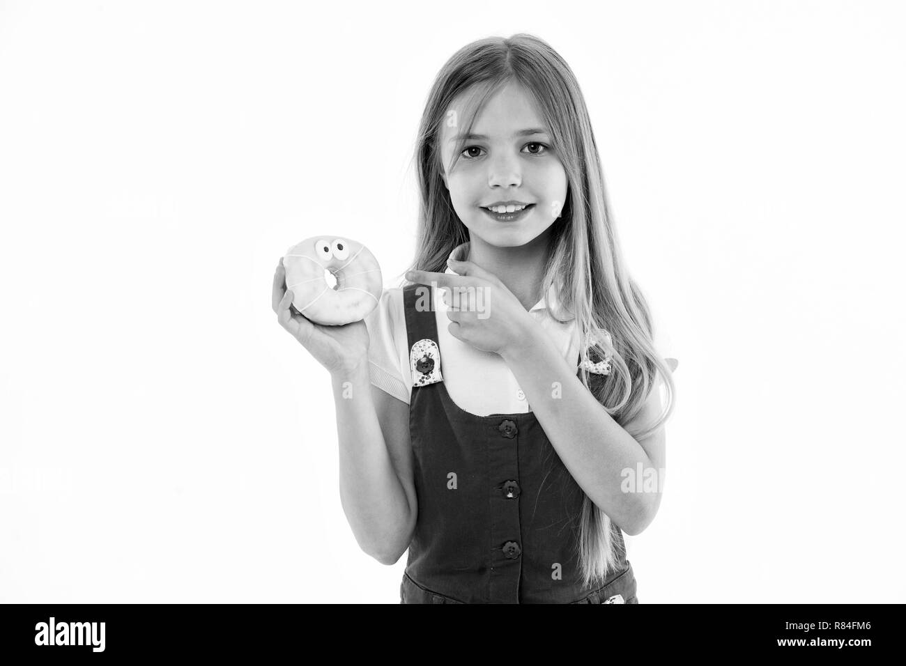 Ragazza con un grande sorriso holding ciambella. Dessert animata, smaltate bagel con gli occhi. Kid puntando alla dolcezza, dente dolce cielo. Bambino con capelli lunghi che indossa abito rosa isolato su sfondo bianco. Foto Stock