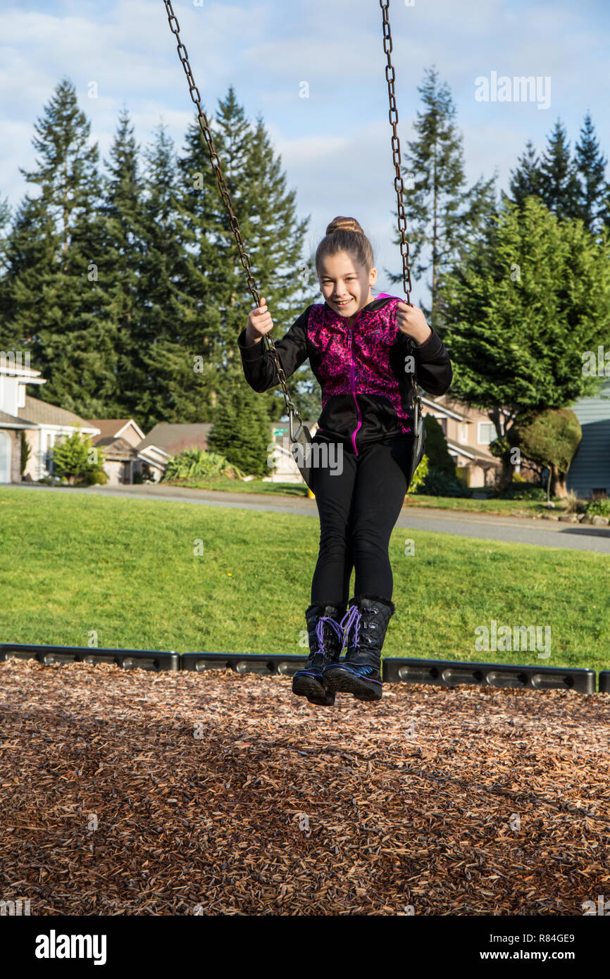 Issaquah, Washington, Stati Uniti d'America. Dieci anni di ragazza seduta su un altalena in un parco giochi. (MR) Foto Stock