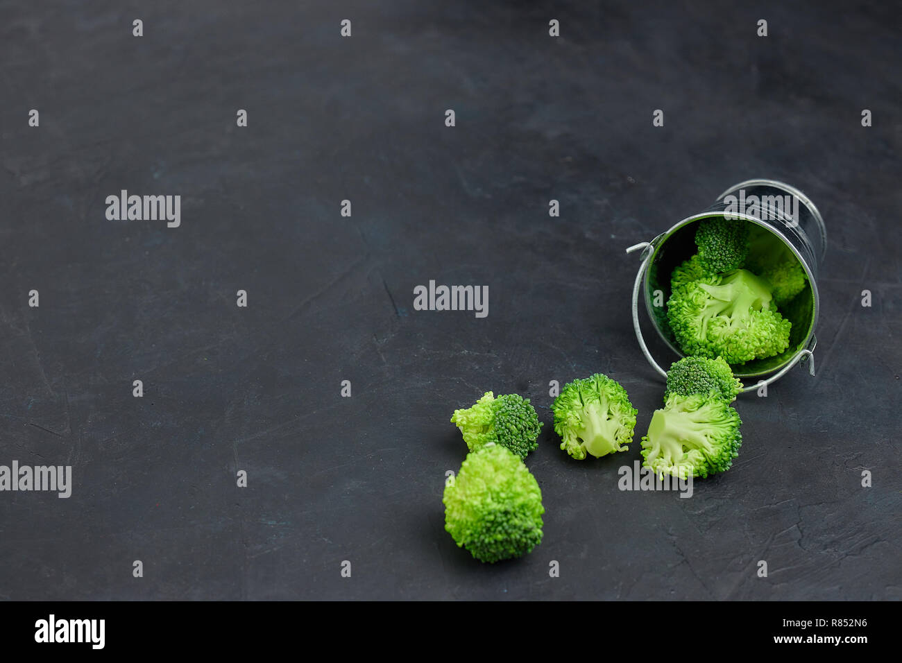Placer broccoli verdi segmenti da un piccolo cucchiaio. Mangiare sano pattern su sfondo scuro. Spazio Copia vista dall'alto. Cibo vegetariano. Foto Stock