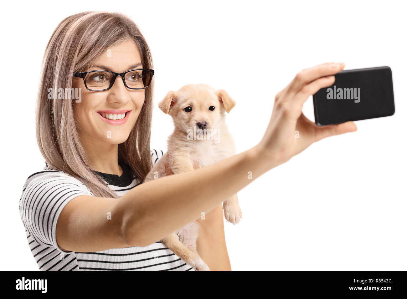 Giovane donna tenendo un grazioso cucciolo di cane e prendendo un selfie isolati su sfondo bianco Foto Stock