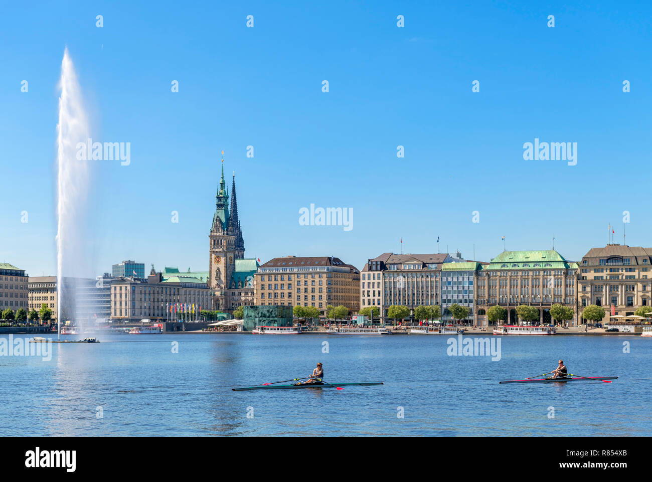 I rematori sculling sul lago Binnenalster con lo skyline della città dietro, Amburgo, Germania Foto Stock