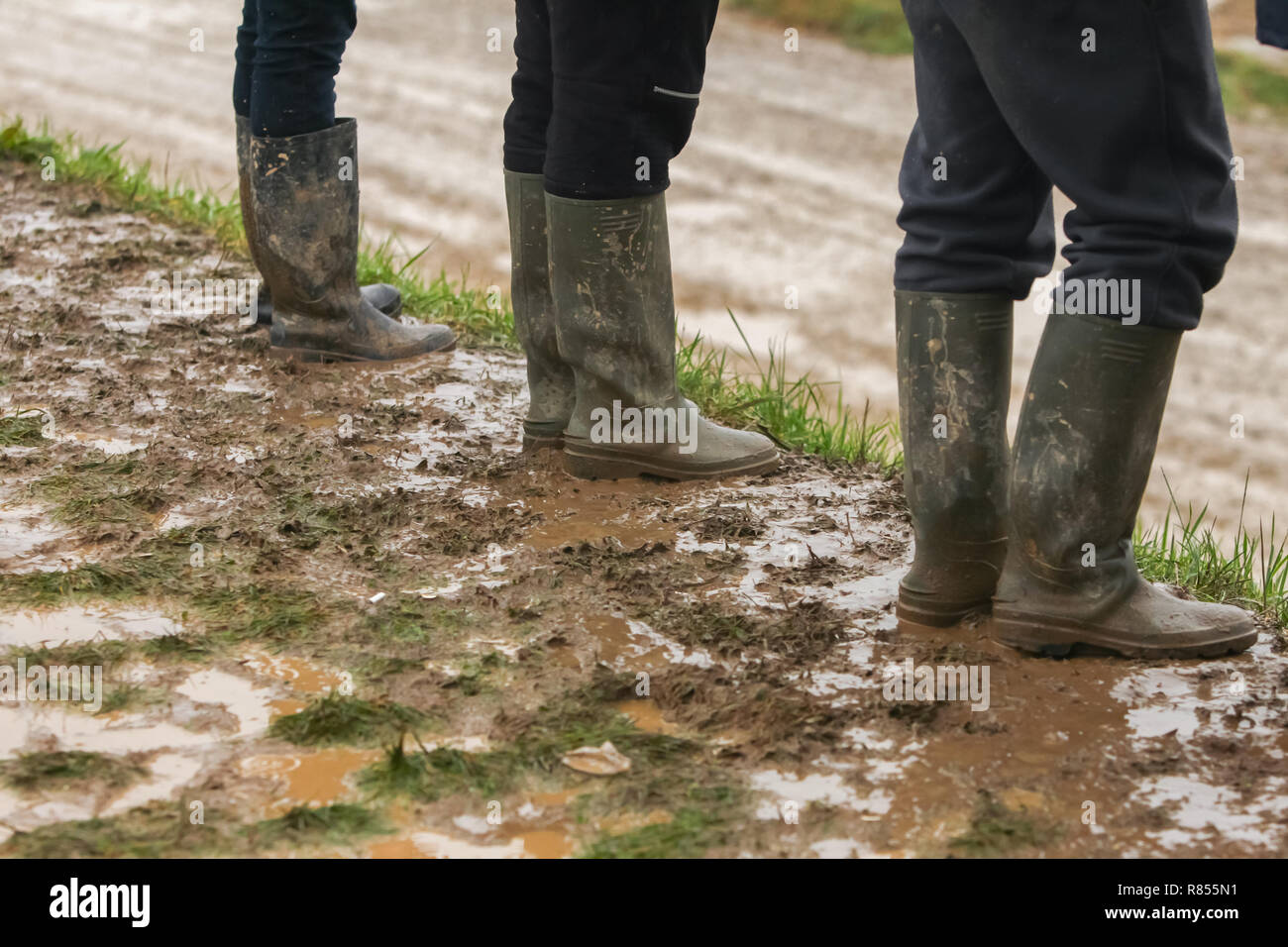 Tre persone in stivali di gomma in piedi nel fango Foto stock - Alamy