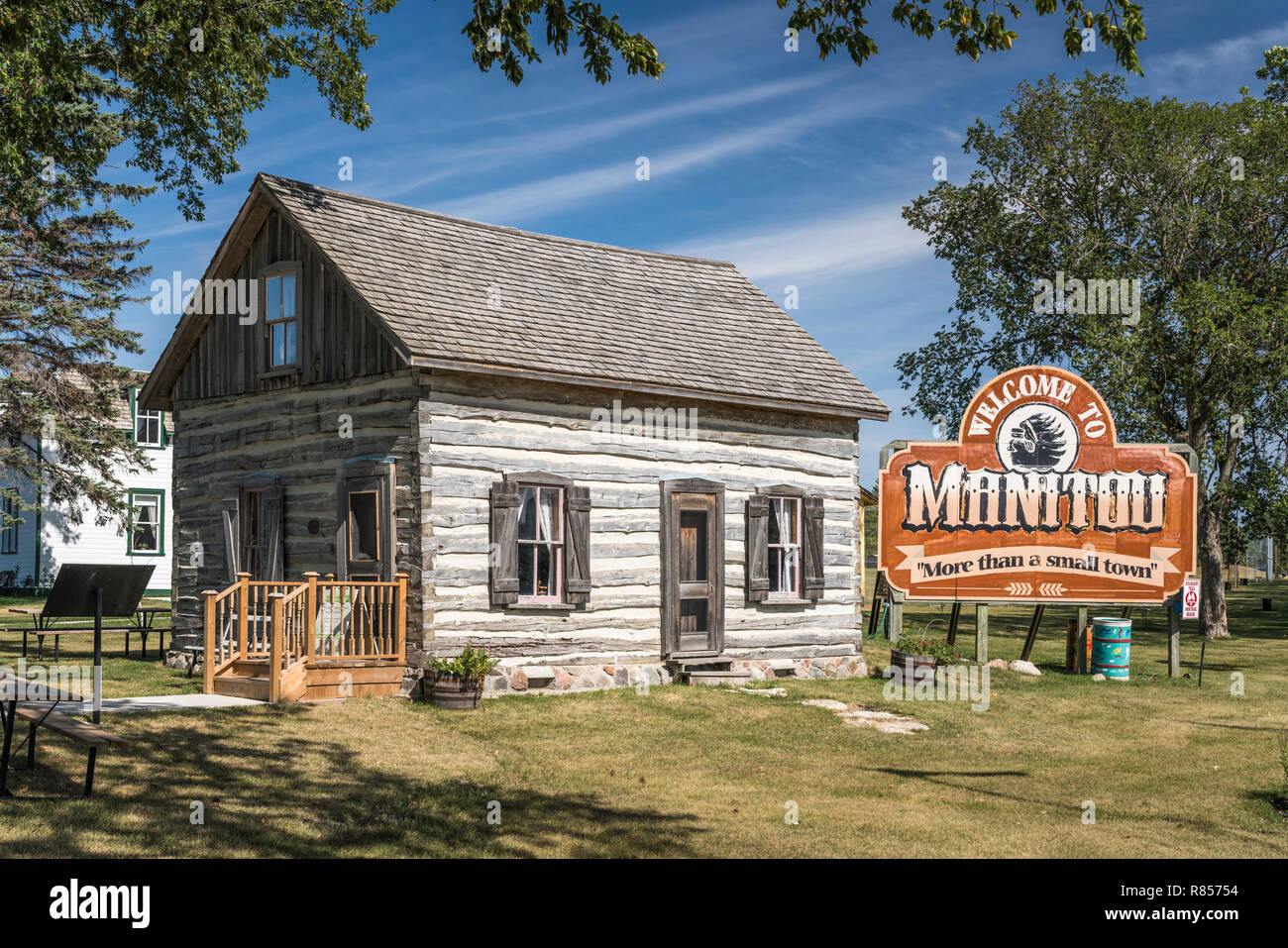 Il Centro Visitatori di log cabin e segno di benvenuto in Manitou, Manitoba, Canada. Foto Stock