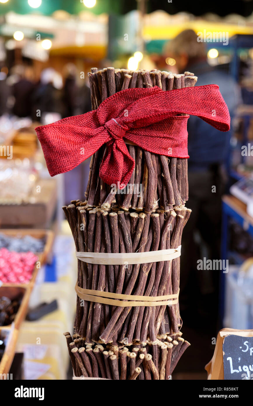 Liquirizia grezza (bastoncini di liquirizia) Glycyrrhiza glabra con un rosso di prua di Natale su una bancarella al mercato di Borough di Natale in Londra England Regno Unito KATHY DEWITT Foto Stock