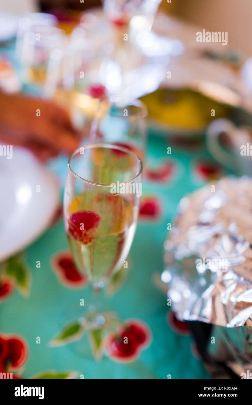 Chiudere atmosferica di bicchieri di champagne con champagne e lamponi flottante con le bolle in vetri scanalati su una tavola durante il giorno del ringraziamento Foto Stock