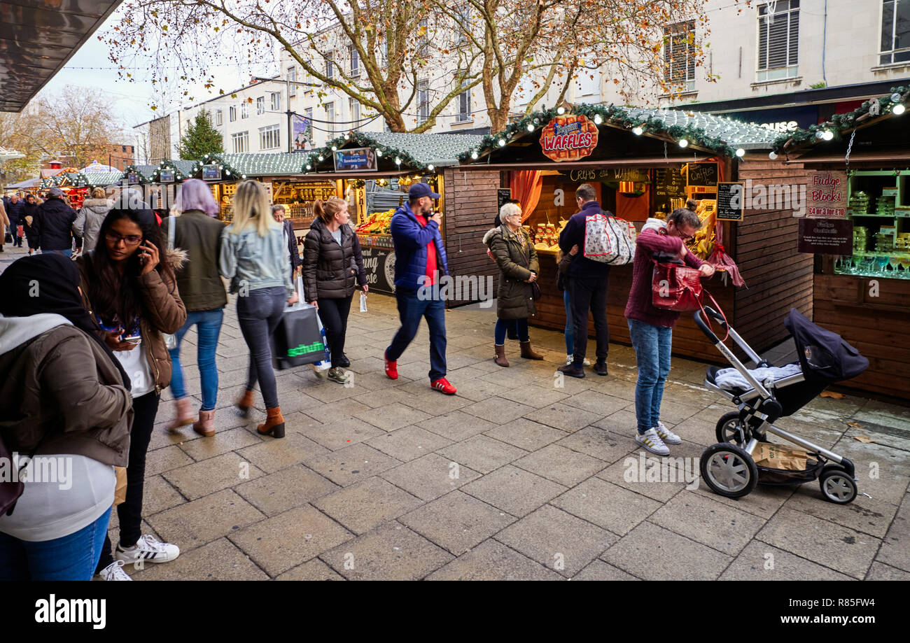 Occupato xmas shopping scena con il mercatino di Natale bancarelle in strada commerciale, Portsmouth, Inghilterra Foto Stock