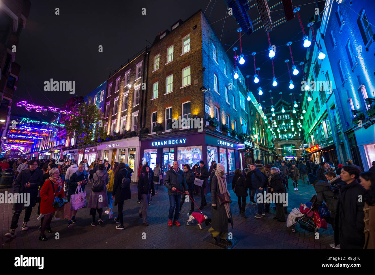 Londra - Novembre 23, 2018: Venerdì nero folla riempire la zona pedonale di vicoli di Carnaby Street, sotto colorate luci di vacanza. Foto Stock