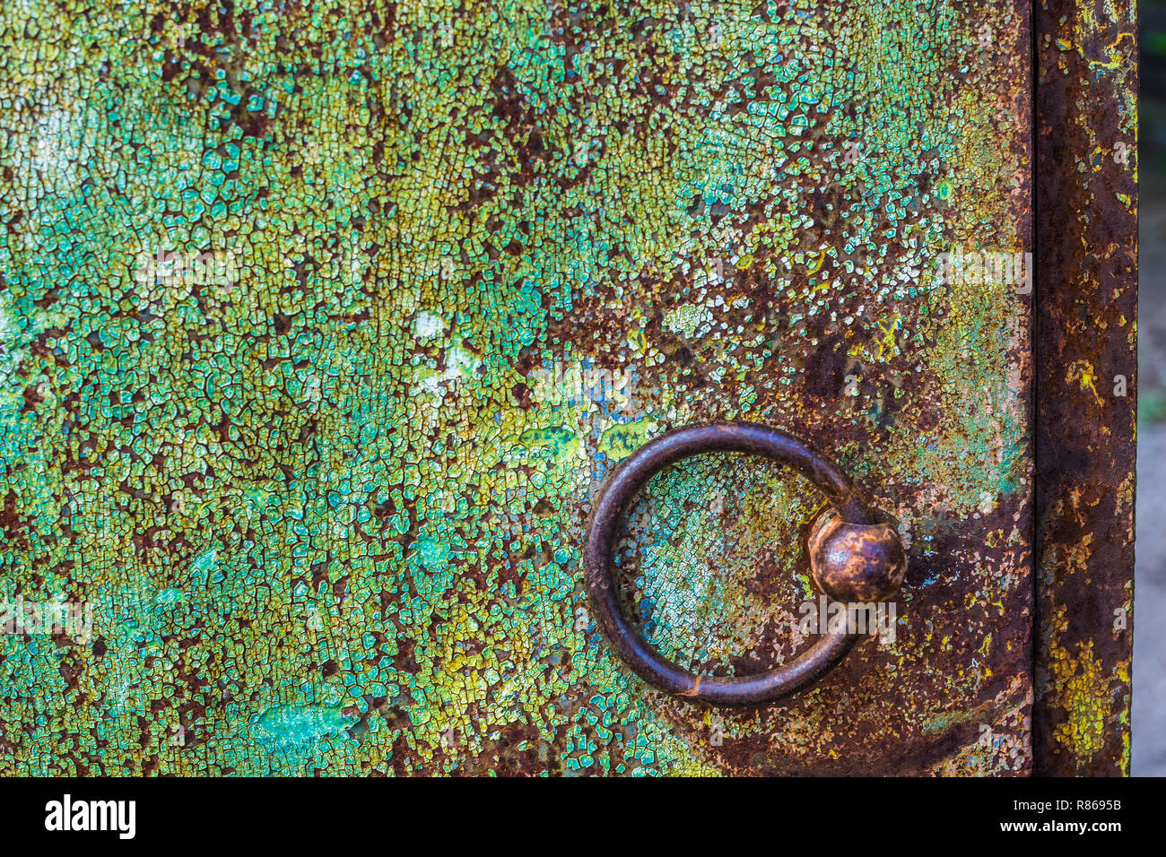 Ferro rotondo da marrone a manopola dello sportello verde sulla parete squallido. Foto Stock