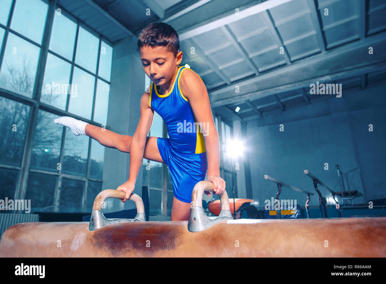 Lo sportivo di eseguire la difficile esercizio ginnico in palestra. Lo sport, esercizio ginnasta, sanità, formazione, atleta concetto. Montare caucasica little boy Foto Stock