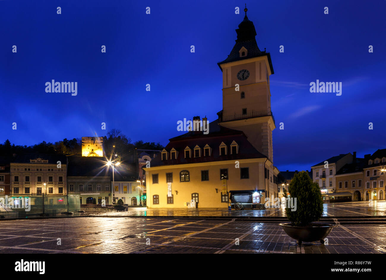 La piazza del Consiglio durante la pioggia in Brasov, Romania. Visualizzare con i famosi edifici di sera e luci di pubblico. Foto Stock