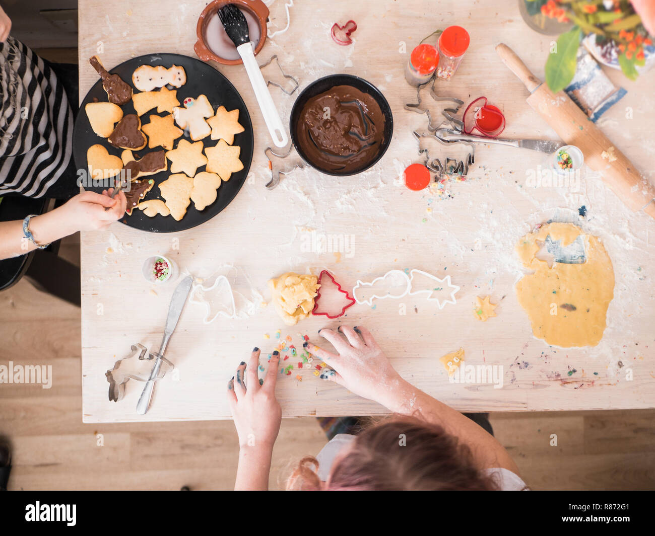 Panificio di natale: Ragazze preparare biscotti di Natale, vista dall'alto con sifferent forniture di cottura, tavolo caotico Foto Stock