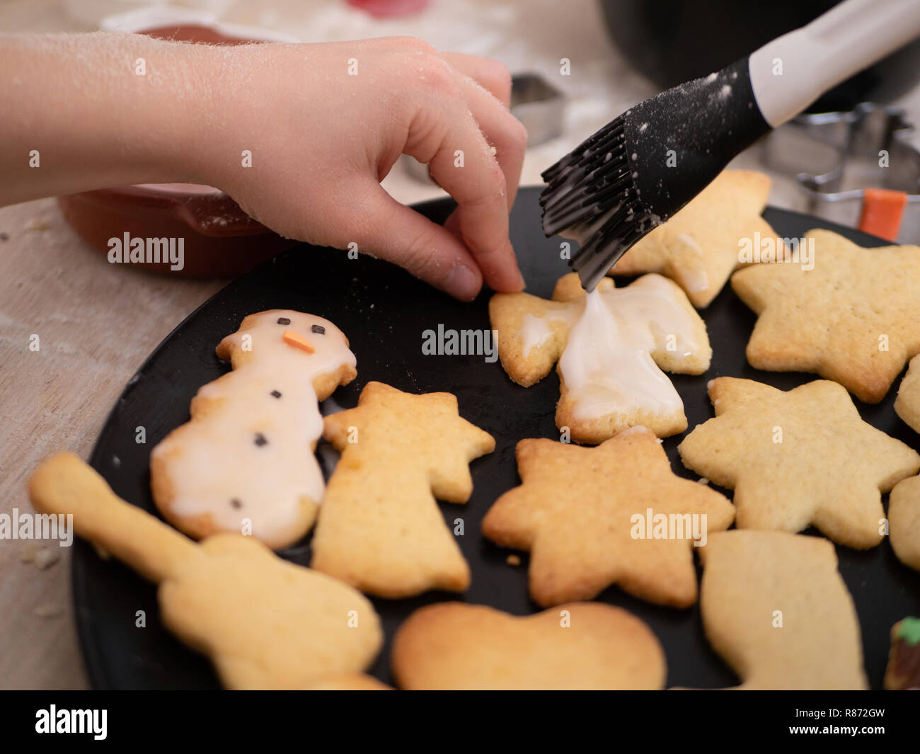 Panificio di Natale: Bambina pittura pasta biscotto con vetri di zucchero, decorazione Foto Stock