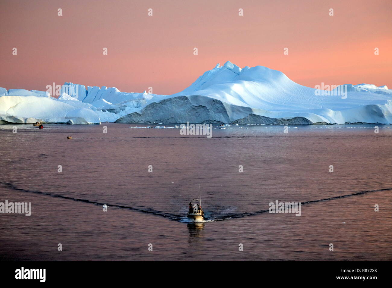 Ilulissat Eisberge am Abend Ein Ausflugsboot eilt im Abendrot Zurück zum Kreuzfahrtschiff. Foto Stock