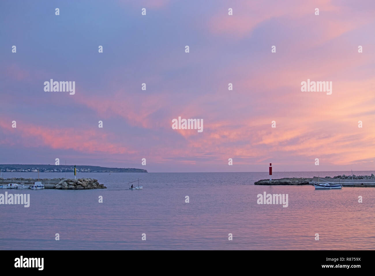 MALLORCA, Spagna - 24 novembre 2018: rosa polverulento tramonto in inverno sci e oceano paesaggio con Pier e barche su Novembre 24, 2018 a Mallorca, Spagna. Foto Stock