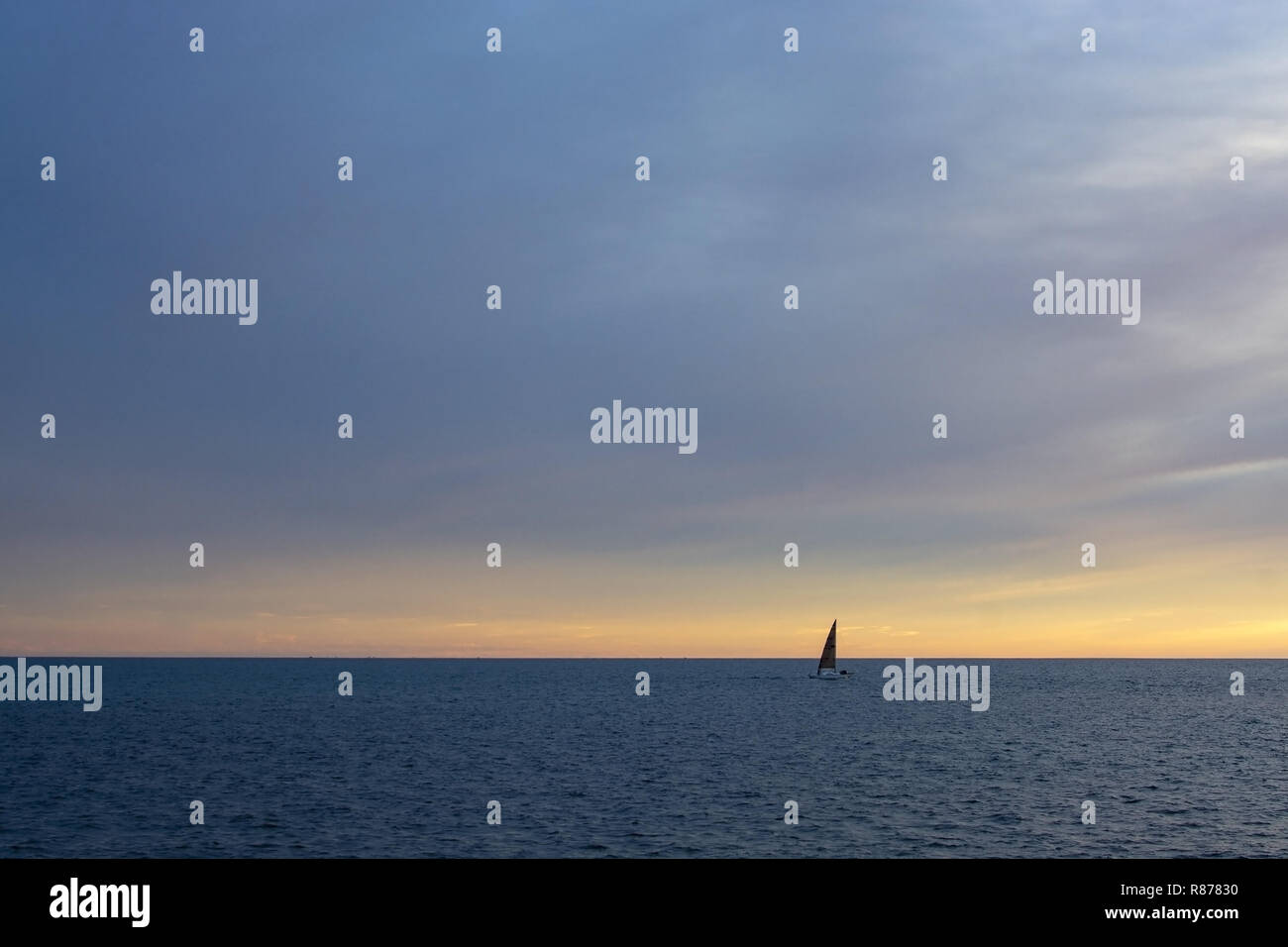 Dritto linea di orizzonte con barca a vela oltre mare mediterraneo in rosa e in blu in novembre a Mallorca, Spagna. Foto Stock