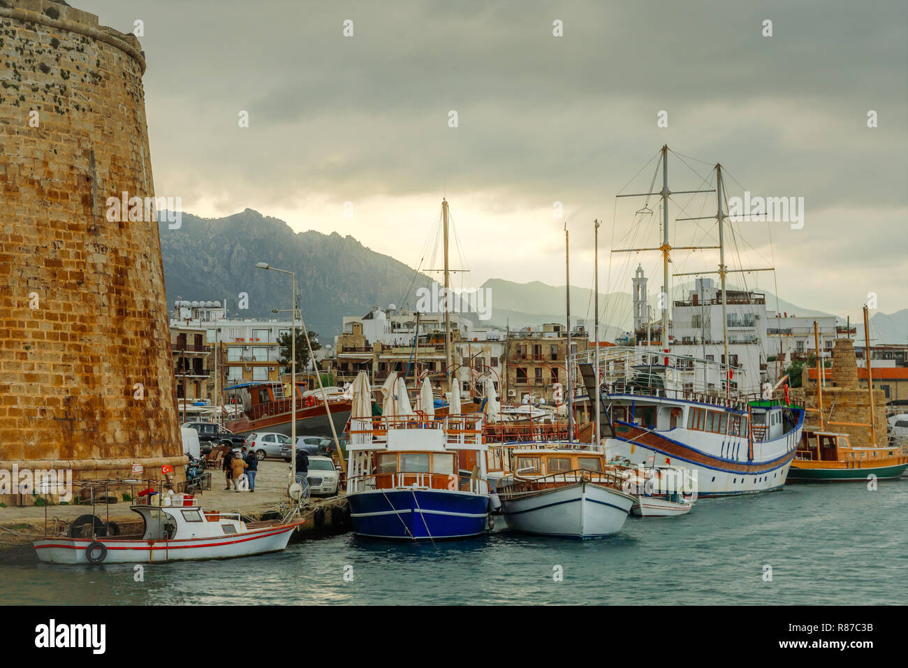Kyrenia o Girne centro storico, vista di marina con molti yacht e barche con il castello veneziano di pareti e montagne sullo sfondo, Nord Foto Stock