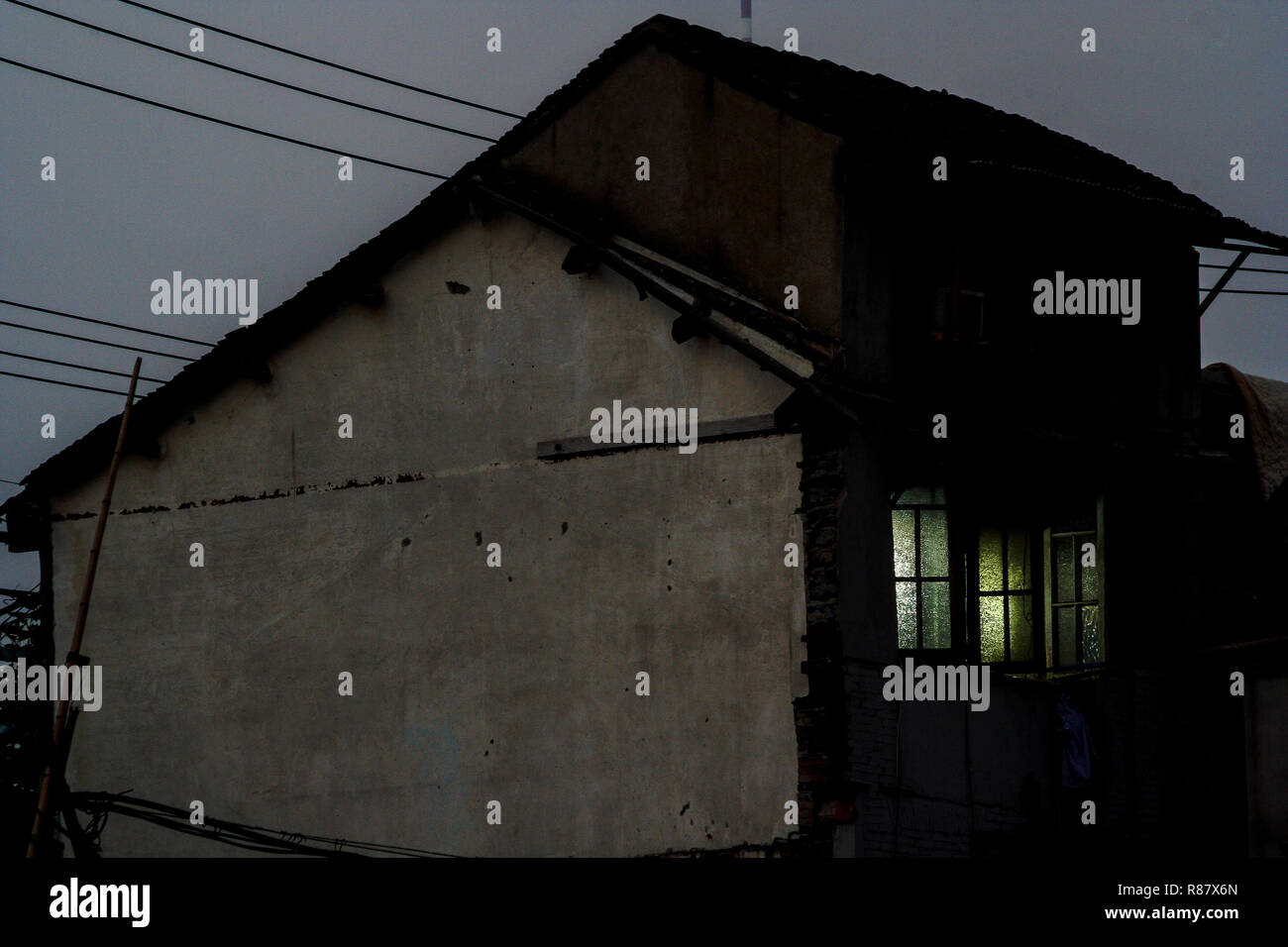 Luce in alcune finestre in un parzialmente demolita casa in Cina a Shanghai. Una famiglia rimanenti ancora vivono lì, per un periodo di tempo limitato. Foto Stock