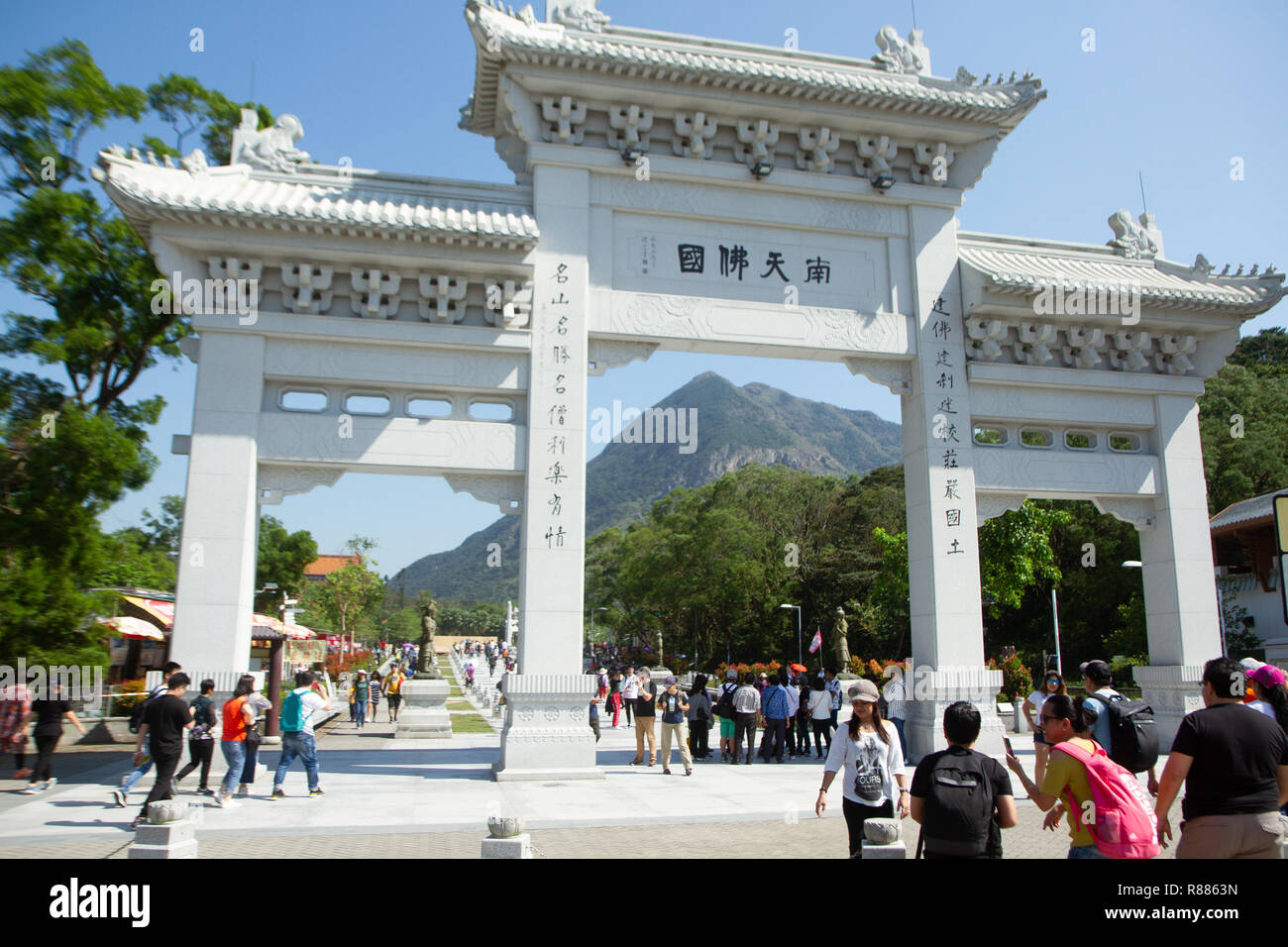 Gateway bianco ingresso al Monastero Po Lin, Isola di Lantau, Hong Kong, Cina, con una folla di persone che entrano nel terreno. Foto Stock Gateway bianco ingresso al Monastero Po Lin, Isola di Lantau, Hong Kong, Cina, con una folla di persone che entrano nel terreno. Foto Stock