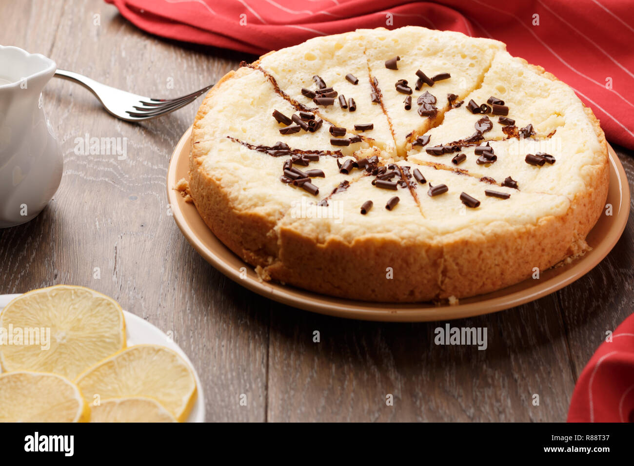 In casa la cheesecake cosparso con scaglie di cioccolato su uno sfondo di legno. Vista laterale Foto Stock