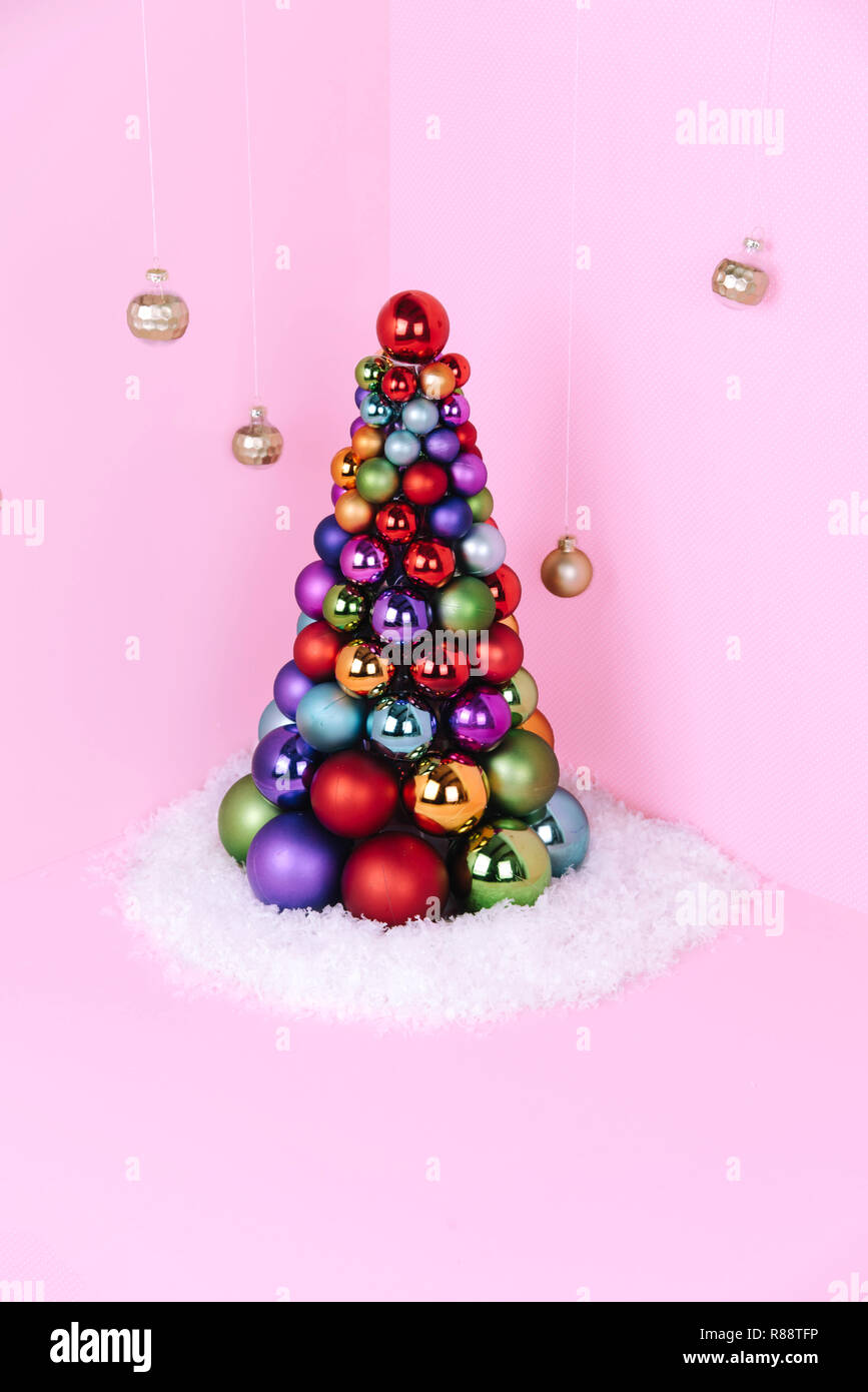 Albero di Natale fatto di decorazione a sfera su sfondo rosa. Foto Stock