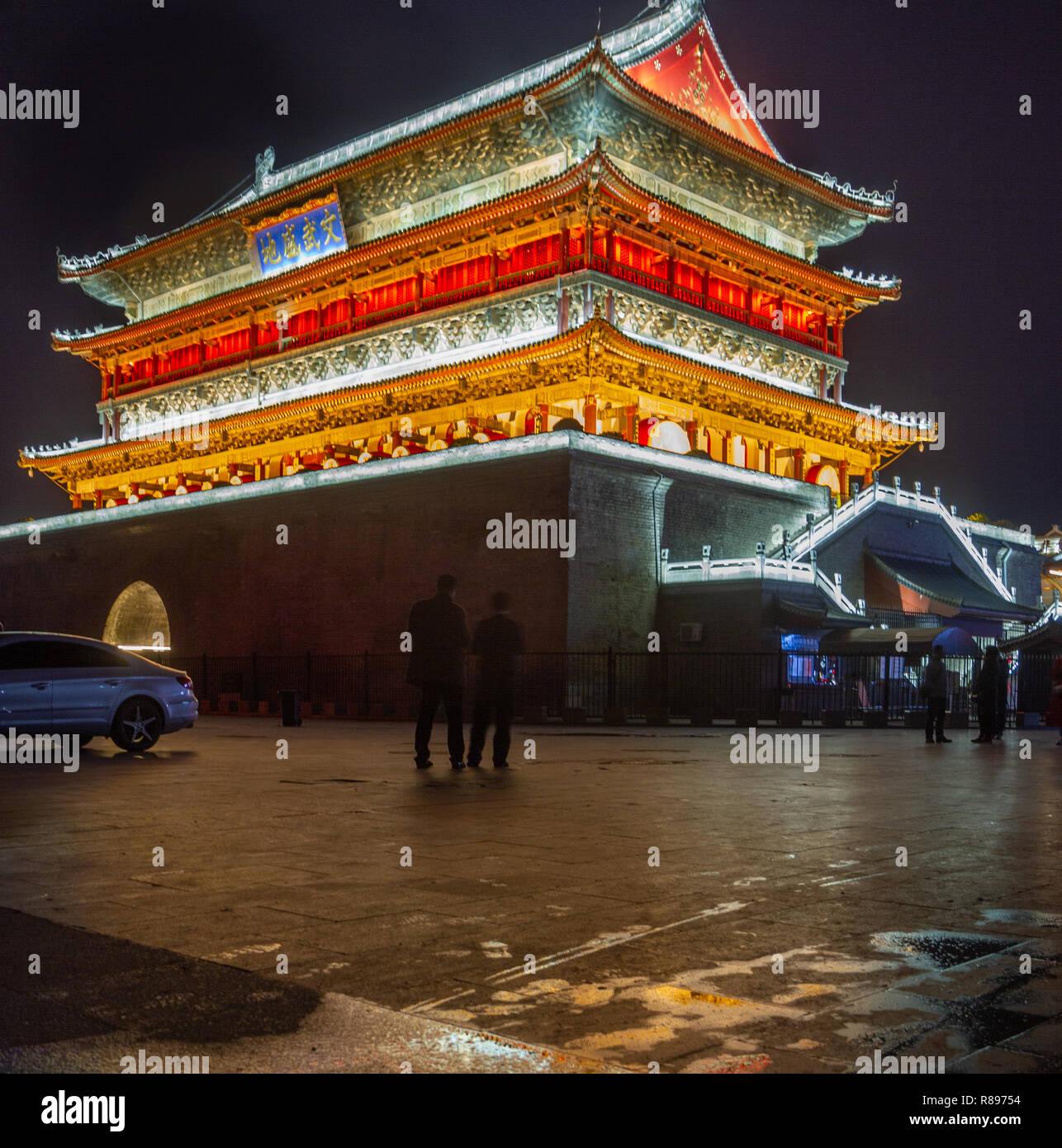 La torre del tamburo di notte, Xian, Cina. Torre è illuminata di notte con soft verde, giallo e arancione si accende. Persone in silhouette a base torre. Foto Stock La torre del tamburo di notte, Xian, Cina. Torre è illuminata di notte con soft verde, giallo e arancione si accende. Persone in silhouette a base torre. Foto Stock