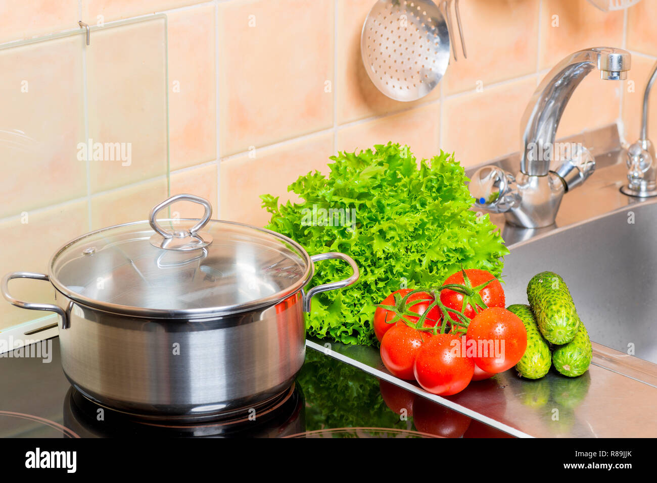 Pulire le verdure e la pentola sul fornello vicino al lavello in cucina close-up Foto Stock