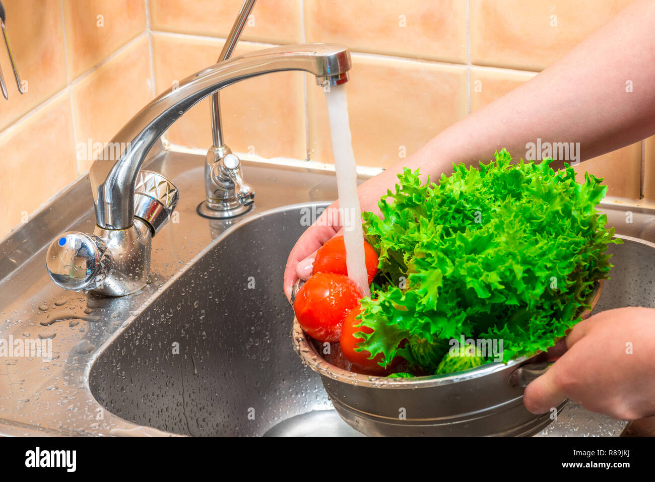 Preparare le verdure per la cottura, risciacquo in acqua corrente Foto Stock