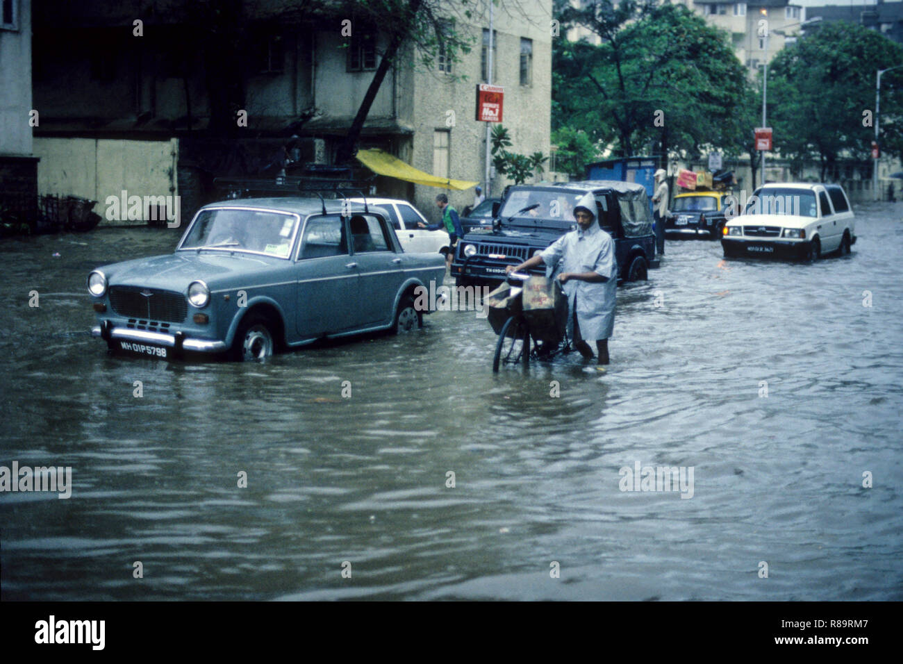 Uomo che cammina con ciclo in inondati di acqua sulla strada, heavy rain, Mumbai Bombay, Maharashtra, India Foto Stock