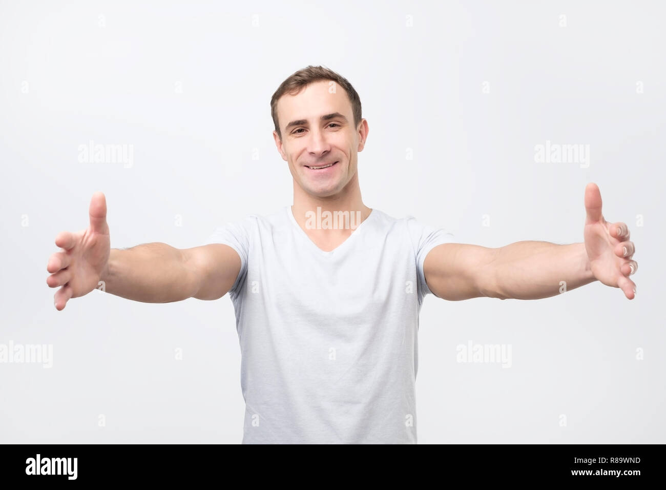 Bel ragazzo tirando le mani verso la telecamera e sorridente cordiale alla telecamera che vogliono abbraccio Foto Stock