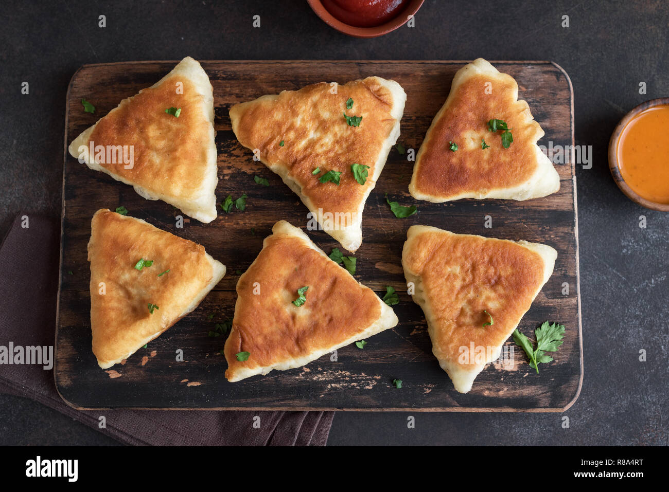 Fritte pasticci di carne, samsa, samosas, echpochmak - Le carni tradizionali torte ripiene o torte vegetariane su sfondo rustico, vista dall'alto. Foto Stock