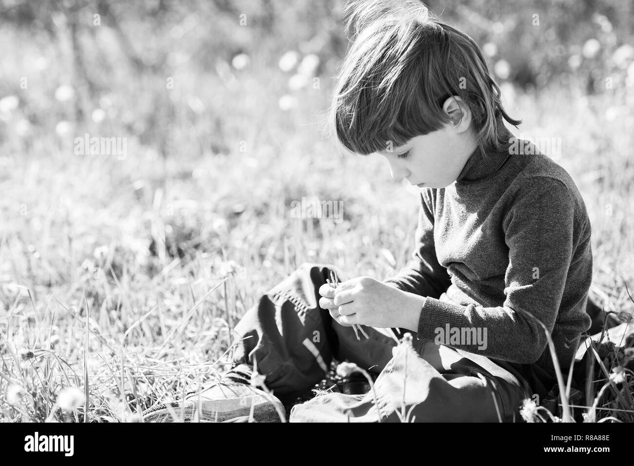 Un bambino si siede e pensa. Ragazzo sognando su erba e triste. Foto Stock