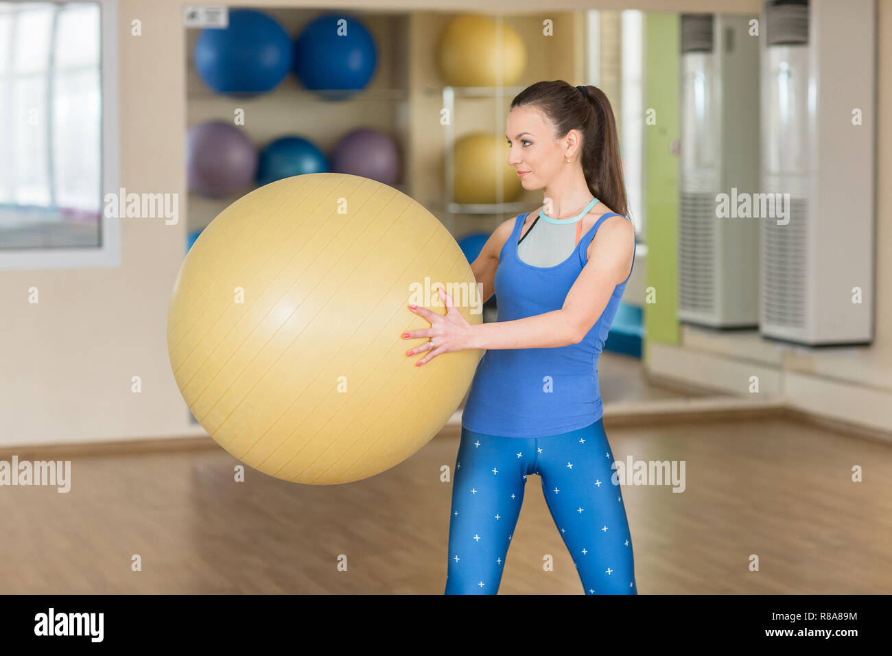 Giovane donna fitness facendo le piste con fitball presso la palestra. Formazione sportiva nel fitness studio. Foto Stock