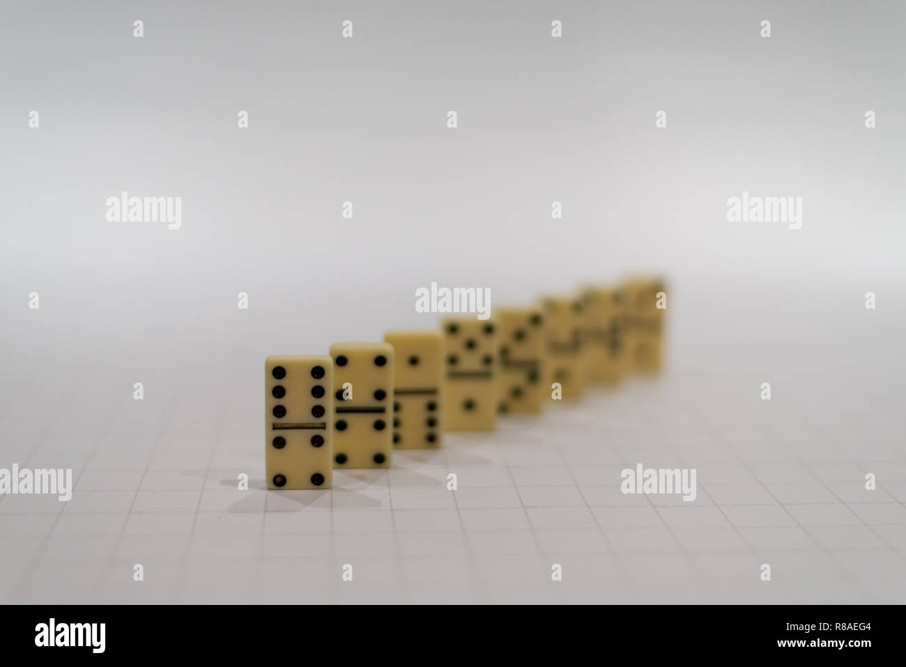 Fila di domino giallo pezzi o blocchi sullo sfondo bianco con il primo pezzo a fuoco Foto Stock
