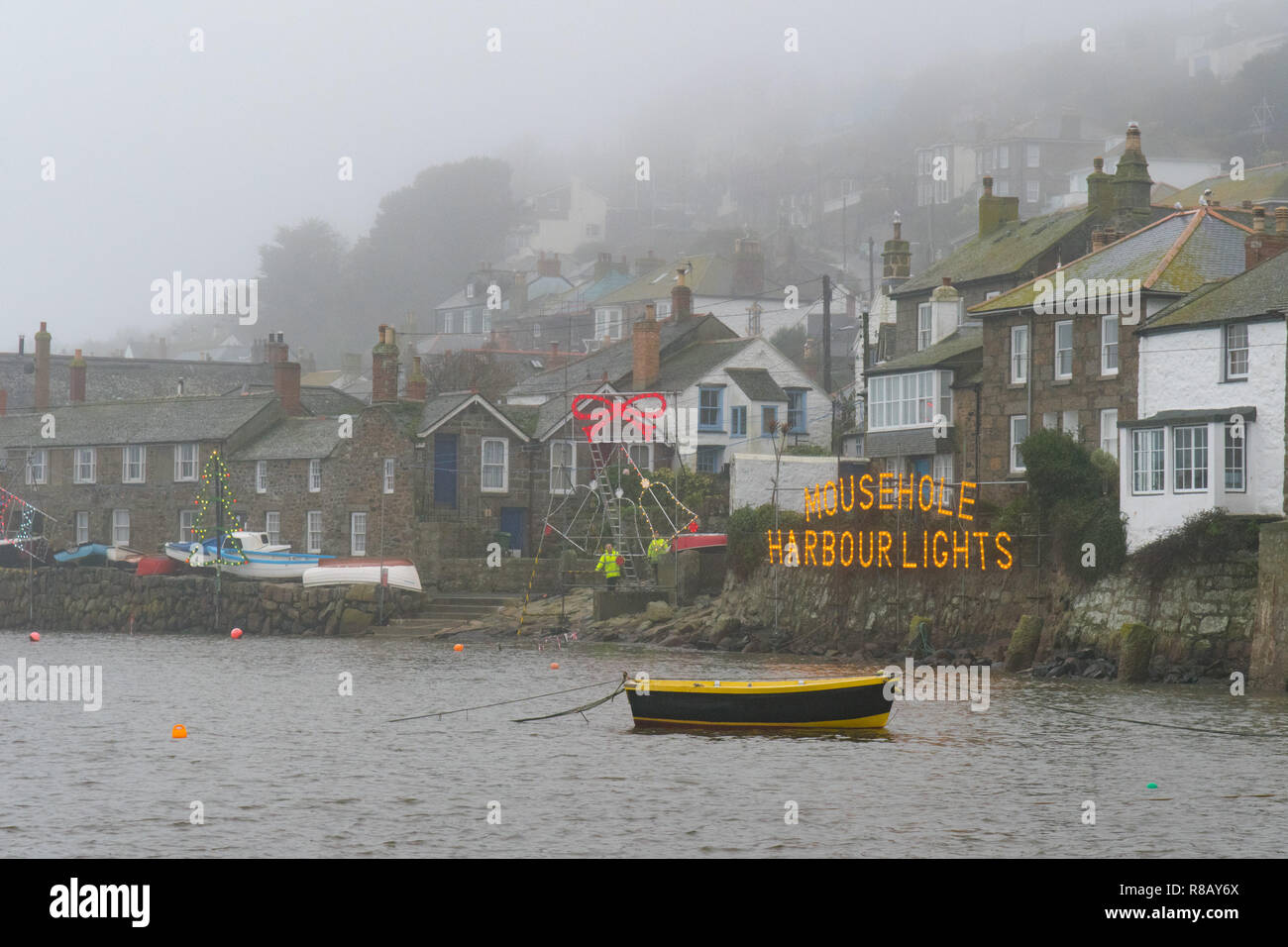 Mousehole, Cornwall, Regno Unito. Il 15 dicembre 2018. Regno Unito Meteo. I volontari sono stati di effettuare ultimi aggiustamenti per le luci del Porto a Mousehole questa mattina nel nebbioso e condizioni di umidità in vista del Gran accendere questa sera. Oltre un migliaio di persone sono suscettibili di pack nel piccolo villaggio di Porto stasera per vedere la famosa in tutto il mondo le luci di Natale. Credito: Simon Maycock/Alamy Live News Foto Stock